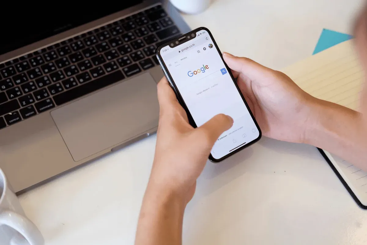 Personne consultant son téléphone à son bureau, un ordinateur portable à côté