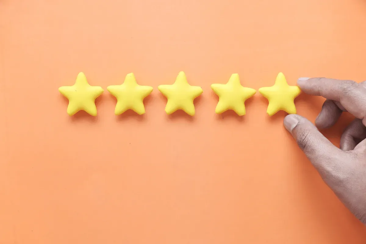 Main désignant cinq étoiles, symbole d’un avis client cinq étoiles