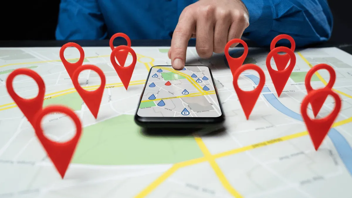 Main qui consulte une carte Google Maps sur smartphone, entourée de repères d’entreprises locales